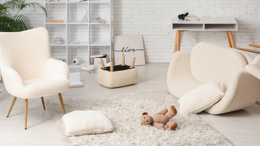Soft, quiet living room with light-colored chairs, a plush rug, and natural daylight, creating a calm and unpressured atmosphere.